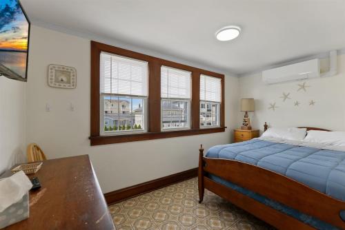 113 E 24th Ave, 2nd Floor في شمال وايلدوود: غرفة نوم بسرير ومكتب ونوافذ
