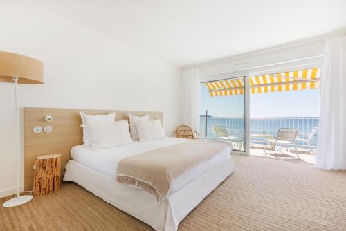 1 dormitorio con cama grande y ventana grande en Belle Vue Hôtel, en Cavalaire-sur-Mer