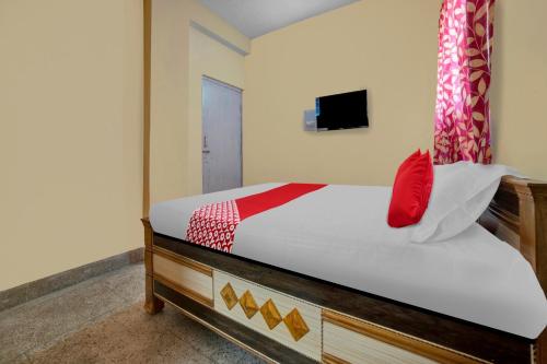Un dormitorio con una cama con una almohada roja. en OYO Flagship Hotel Sweet And Soul, en Jamshedpur
