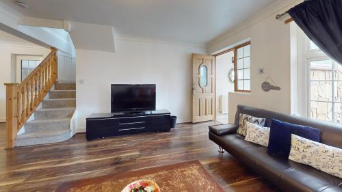 a living room with a couch and a flat screen tv at Charming 5 bedroom house in Grays in Grays Thurrock