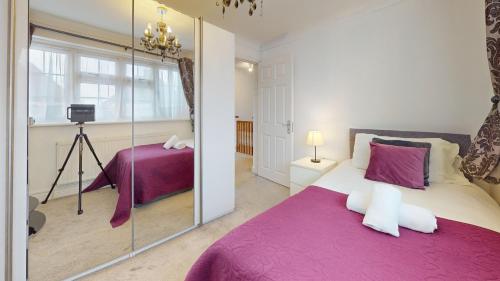 a bedroom with a purple bed and a mirror at Charming 5 bedroom house in Grays in Grays Thurrock