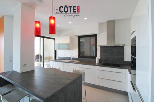 une cuisine avec des armoires blanches et un comptoir noir dans l'établissement Villa Horizon Bleu, à Sausset-les-Pins