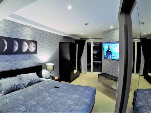 a bedroom with a bed and a flat screen tv at Plein centre-ville : appartement d'angle moderne in Pattaya Central