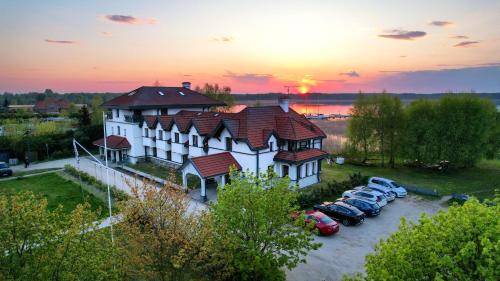 a large building with cars parked in a parking lot at Hotel Joseph Conrad SPA & Wellness in Pisz