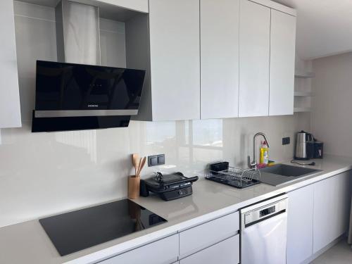 a kitchen with white cabinets and a tv on the wall at Ulu Panorama Residence in Alanya