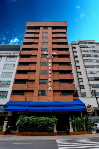 a hotel building with a blue awning in front of it at Hotel Obelisco in Cali