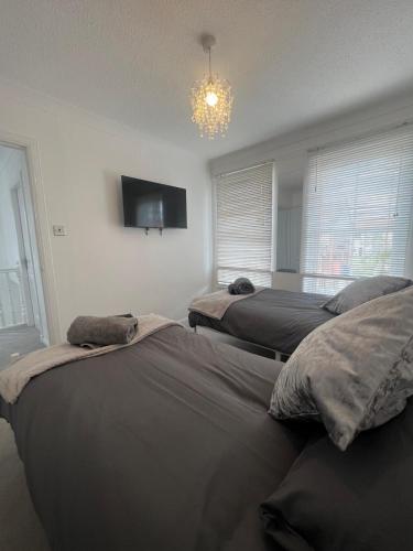a bedroom with two beds and a tv on the wall at No 6, Ayr, 140m2, New Decor 2024, 3bedroom, detached house, with private gardens in Ayr
