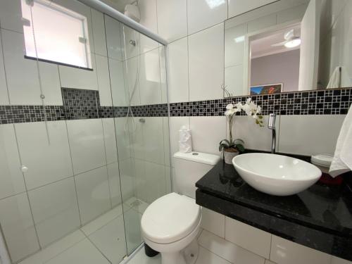 a white bathroom with a toilet and a sink at Mar Y Suites in Cabo Frio