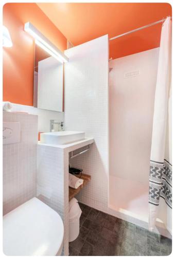 La salle de bains orange est pourvue de toilettes et d'un lavabo. dans l'établissement Charmant appartement proche du Musée Picasso, à Paris