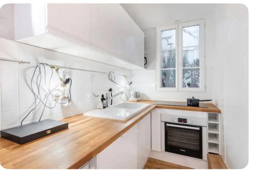 une cuisine blanche avec un évier et un comptoir dans l'établissement Charmant appartement proche du Musée Picasso, à Paris