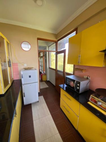 cocina con armarios amarillos y nevera blanca en Sikandar Bagh Cottages en Nathia Gali