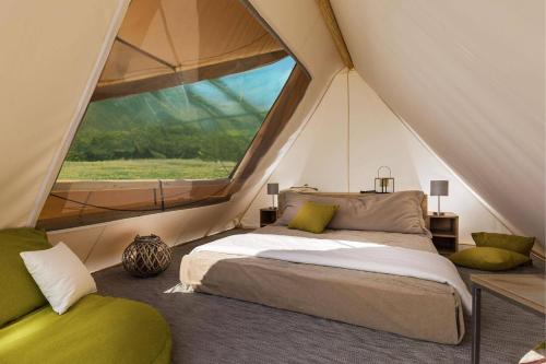 a bedroom in a tent with a bed and a window at Banki Green Istrian Village - Holiday Homes & Glamping Tents in Bašići