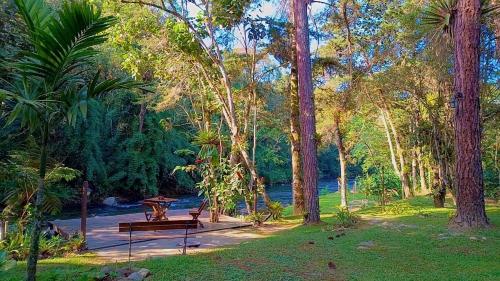 a park with a bench and a picnic table and trees at Pousada Bosque do Visconde in Visconde De Maua