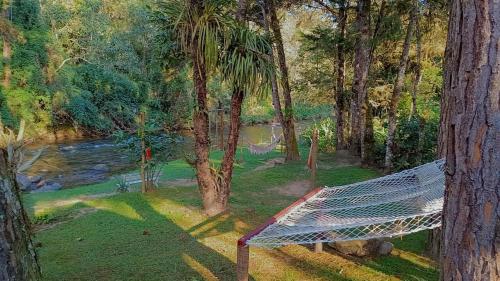 a painting of a hammock in front of a river at Pousada Bosque do Visconde in Visconde De Maua