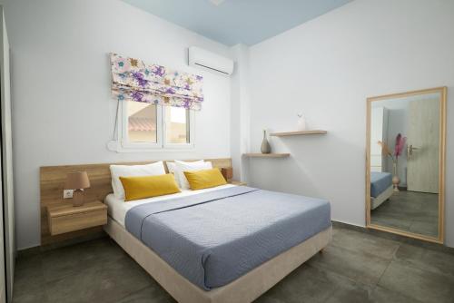 sypialnia z łóżkiem z żółtymi poduszkami i lustrem w obiekcie Votsalo w Jerapetrze