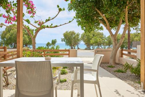 a white table and chairs on a patio with trees at Votsalo in Ierápetra