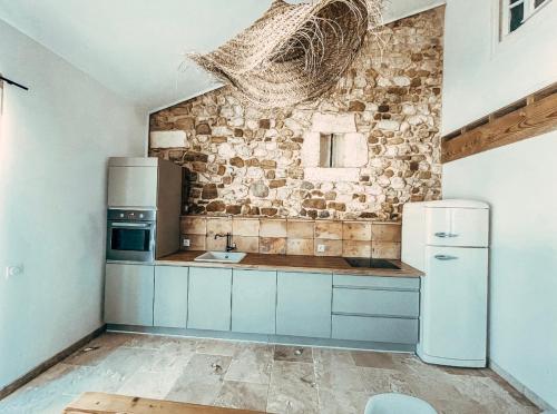 eine Küche mit einem weißen Kühlschrank und einer Steinmauer in der Unterkunft Le Clos Bohème - Baron in Baron