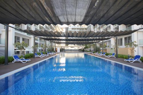 duży basen w budynku z krzesłami w obiekcie Silk Valley - Modern Studio With Pool And Gym w Abu Zabi