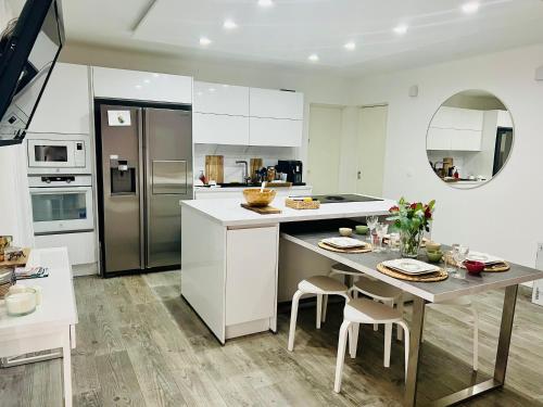 une cuisine blanche avec une table et un réfrigérateur dans l'établissement Superbe Rez-de-Villa 6p calme & plage à pied, au Pradet
