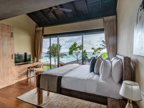 a bedroom with a large bed and a large window at DORMERO Hotel Sri Lanka Hikkaduwa Beach in Hikkaduwa