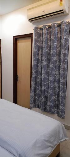 a bedroom with a bed and a window with curtains at Hotel Saffron in Meerut