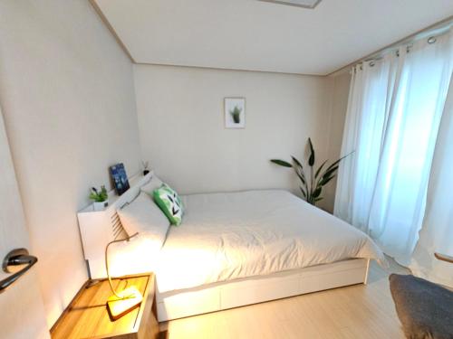 um quarto branco com uma cama e um candeeiro em My comfortable second house em Seul