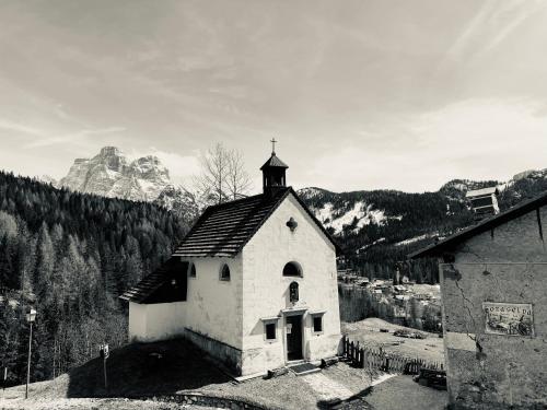 una pequeña iglesia blanca con un campanario en las montañas en Garní Ladinia en Pescul