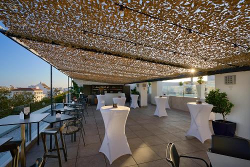 un restaurante con mesas blancas, sillas y luces en Hotel Bécquer, en Sevilla