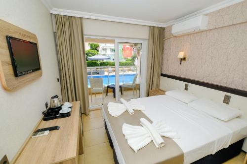 um quarto de hotel com uma cama e uma televisão em Moni Hotel em Marmaris