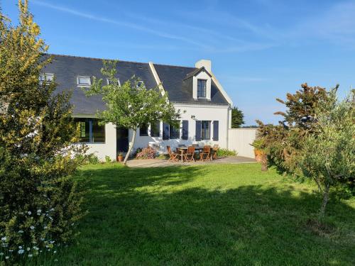 a white house with a table and chairs in the yard at Maisons de vacances 4* à Belle ile en Mer, 5 chambres, 2 salles de bains, avec jardins privatifs in Bangor