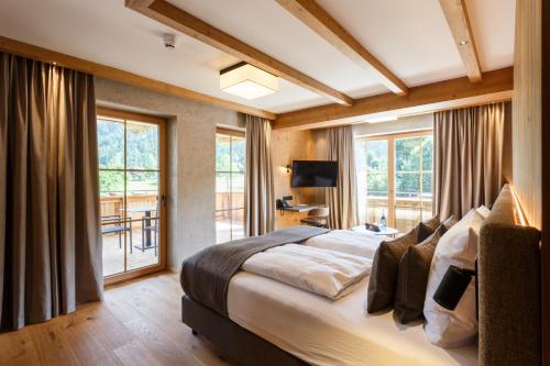 a bedroom with a large bed and a balcony at NOVA Moments Boutique Hotel in Pertisau