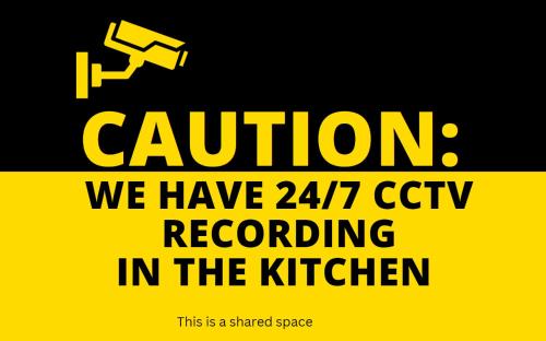 a sign that says caution we have cctv recording in the kitchen at Merj's Guest House in Wolesly in Winnipeg