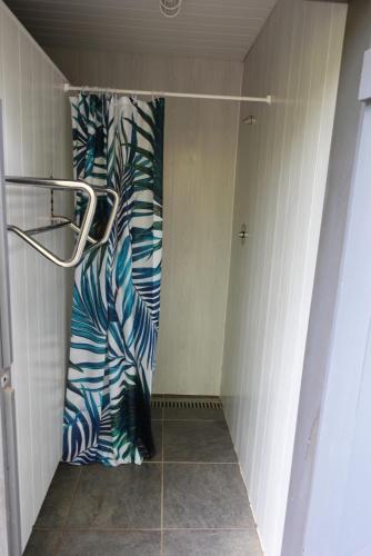 La salle de bains est pourvue d'une douche et d'un rideau bleu et blanc. dans l'établissement Camping Moulin de la Geneste, à Condat-sur-Ganaveix