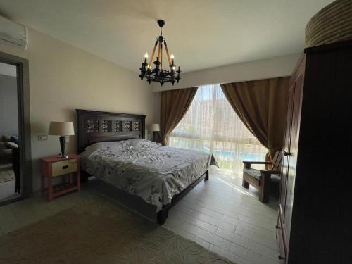 a bedroom with a bed and a chandelier and a window at Beautiful chalet in Il Monte Galala المونت جلالة ch15-01-01 in Ain Sokhna