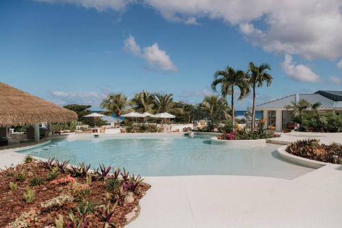 Tortola IslandにあるLong Bay Beach Resortのヤシの木と傘が備わるリゾートのプールを利用できます。