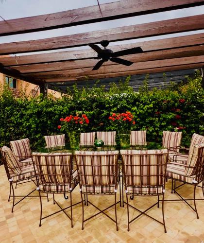 een patio met een tafel met stoelen en een plafondventilator bij Villa Jenna in Marrakesh