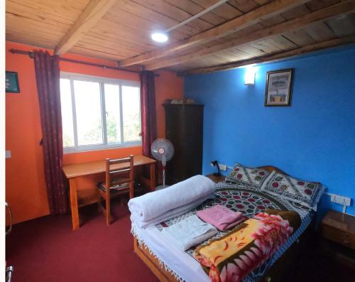 a bedroom with a bed and a desk and a window at Namaste Home Stay in Dhulikhel