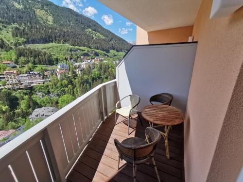 a balcony with chairs and a table with a view at Panorama Spa Lodges DAS.SCHILLER in Bad Gastein