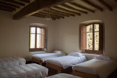 four beds in a room with three windows at Can Traver de Besalú in Maia de Montcal