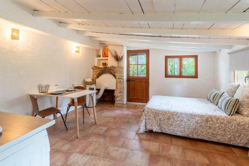 Un dormitorio con una cama y una mesa y una cocina. en Maison Marvic, Studio dans les pins, en Apt