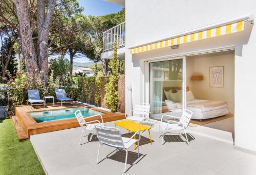 patio con piscina, cama y sillas en Belle Vue Hôtel, en Cavalaire-sur-Mer