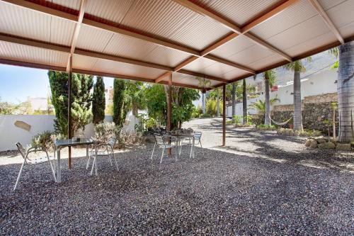 a patio with tables and chairs under a roof at Las Palmeras in Güimar