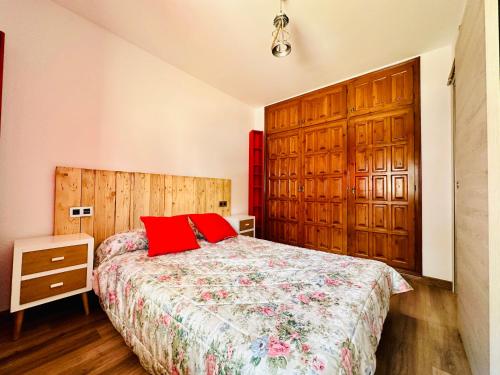 Un dormitorio con una cama con almohadas rojas. en PORT AMBAR - Apartamento en la Marina de Empuriabrava - balcón con vistas al canal - playa - wifi, en Empuriabrava