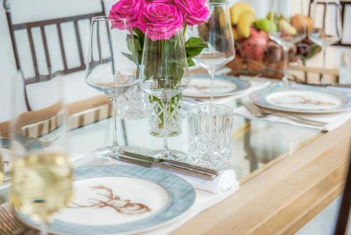 a table with plates and a vase with a pink rose at Panorama Spa Lodges DAS.SCHILLER in Bad Gastein