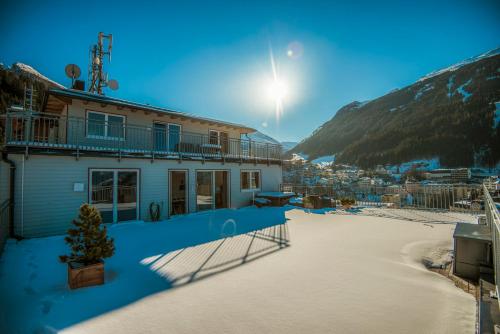 a building with snow on the ground next to a mountain at Panorama Spa Lodges DAS.SCHILLER in Bad Gastein