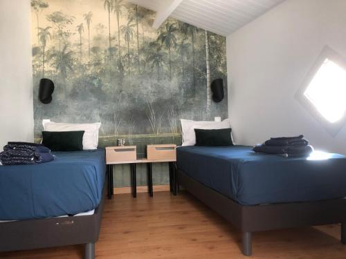 zwei Betten in einem Zimmer mit einem Gemälde an der Wand in der Unterkunft Maison de ville proche mer in Les Sables-dʼOlonne