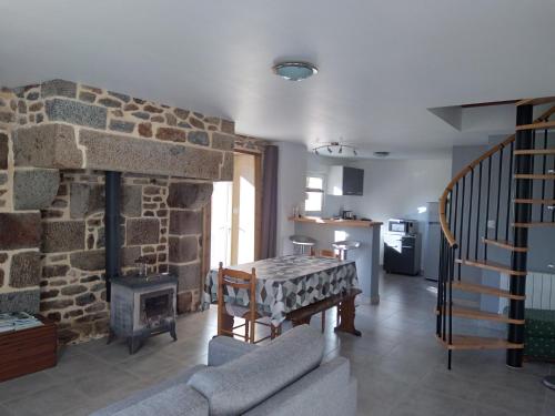 un salon avec une cheminée en pierre et une table dans l'établissement Petite maison à la campagne, à Le PARC