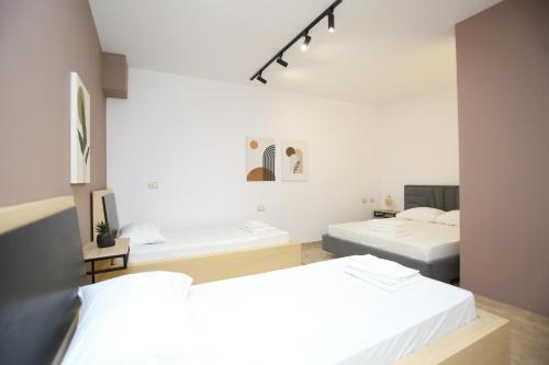 two beds in a room with white walls at TekB Rooms & Apartments in Vlorë