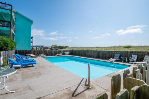 a swimming pool with two chairs and a table at Oceanfront with Pool - Winds VI in Carolina Beach
