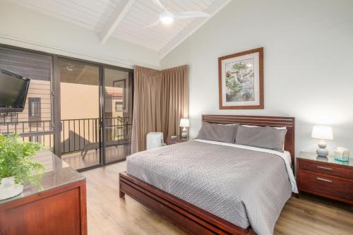 a bedroom with a bed and a tv and a balcony at Kamaole Sands 5-316 in Wailea